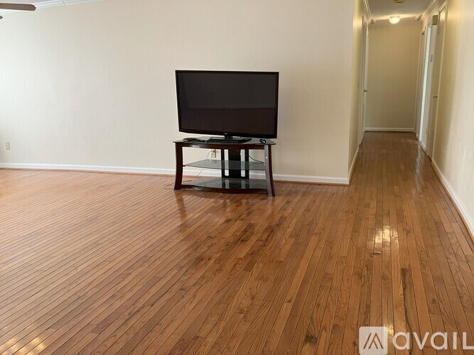 A black television sits on a glass table in a room with wooden floors.