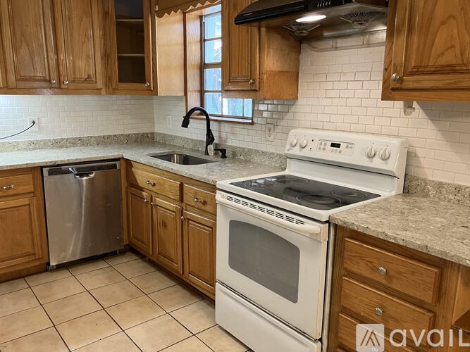 A kitchen with a white stove top oven and a white dishwasher.