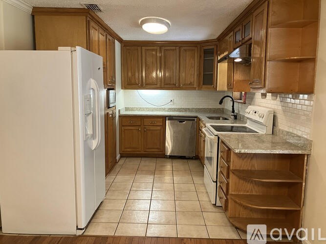 A kitchen with a white refrigerator and brown cabinets.