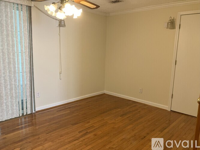 A room with wooden floors and a ceiling fan with lights.