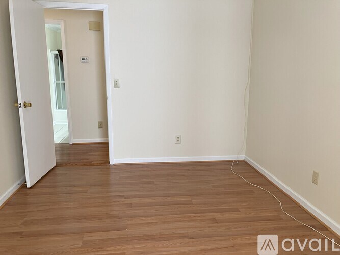 A room with wooden flooring and a doorway leading to another room.