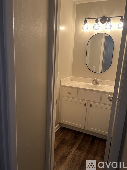 A bathroom with a white counter and a round mirror.