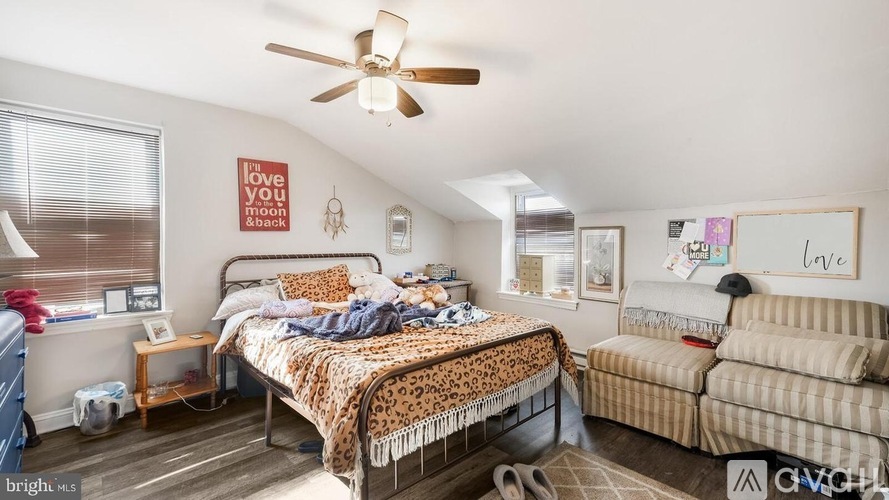 A bedroom with a bed, couch, and a ceiling fan.