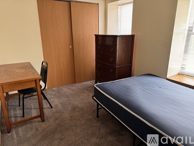 A bedroom with a bed, desk, and chair.