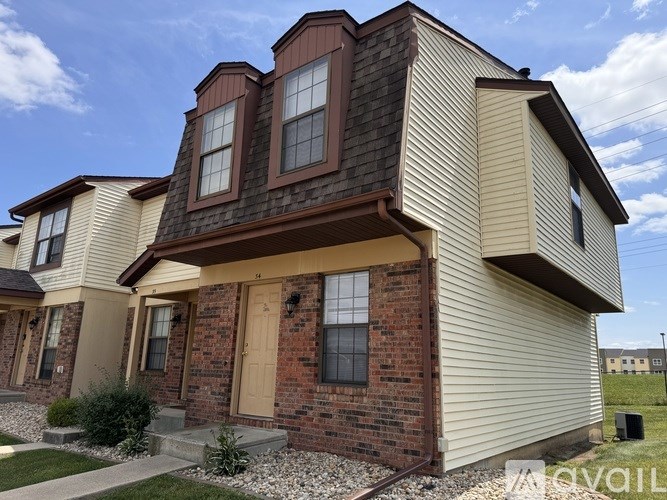 A house with a brown door and a brick wall.