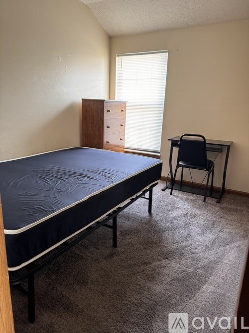 A bedroom with a bed, desk, and chair.