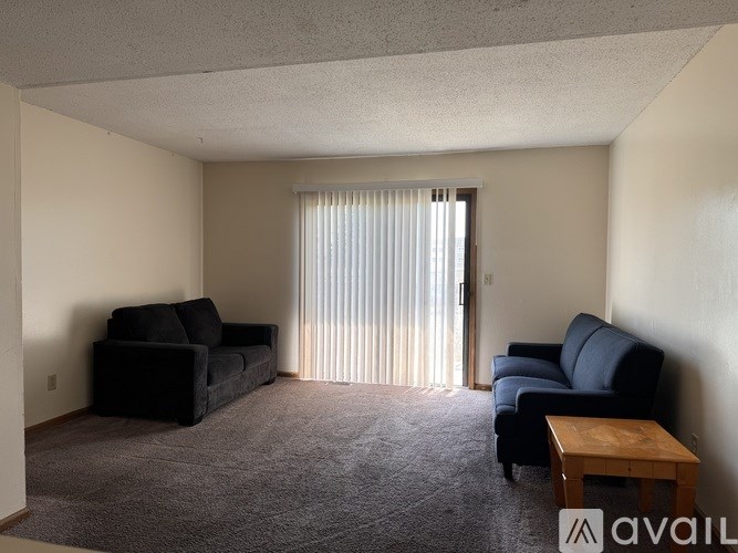 A living room with a black couch, a blue chair, and a wooden coffee table.