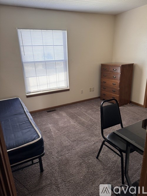 A room with a bed, chair, and a dresser.