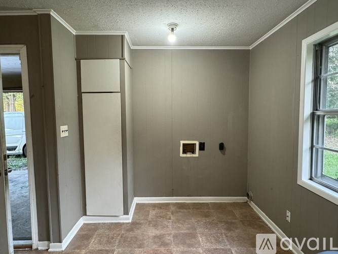 A room with a refrigerator, a small table, and a window.