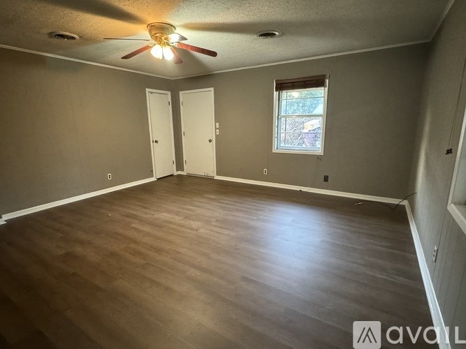 A room with a ceiling fan and wooden flooring.