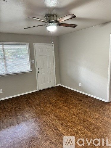 A room with a ceiling fan and wooden flooring.