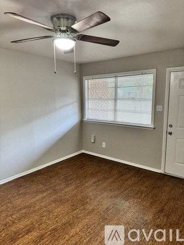 A room with a ceiling fan and wooden flooring.