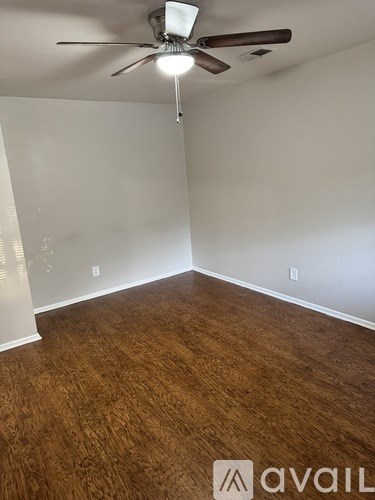 A room with a ceiling fan and wooden flooring.