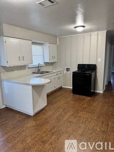 A kitchen with white cabinets and a black trash can.