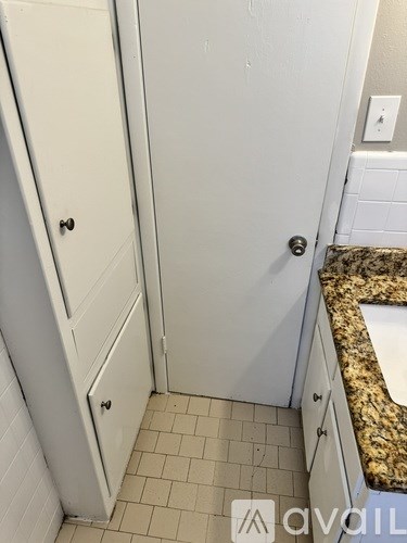 A white door with a black handle is in a bathroom.