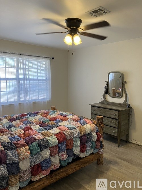 A bedroom with a bed, dresser, and window.