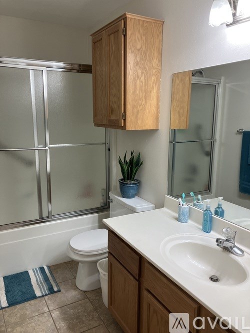 A bathroom with a toilet, sink, and wooden cabinets.