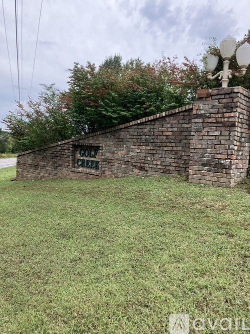 A brick wall with a sign that says "GOLF CREEK".