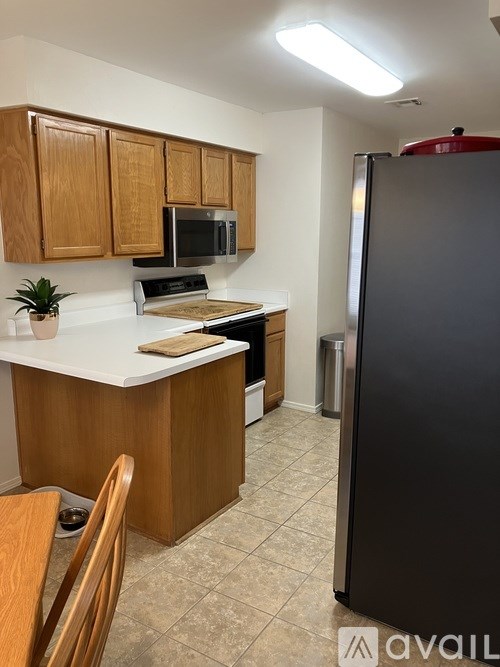 A kitchen with wooden cabinets and a black refrigerator.