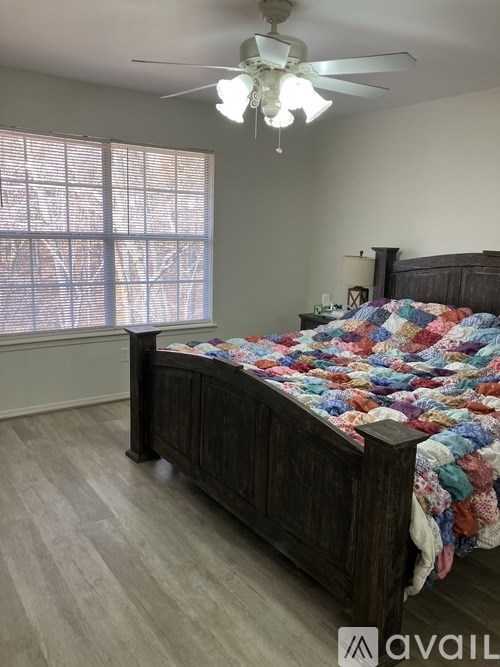 A bedroom with a bed, a ceiling fan, and a window with blinds.