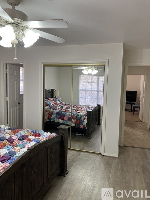 A bedroom with a bed, mirror, and ceiling fan.