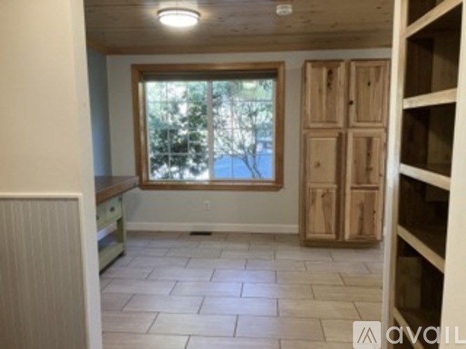 A room with a window and wooden cabinets.