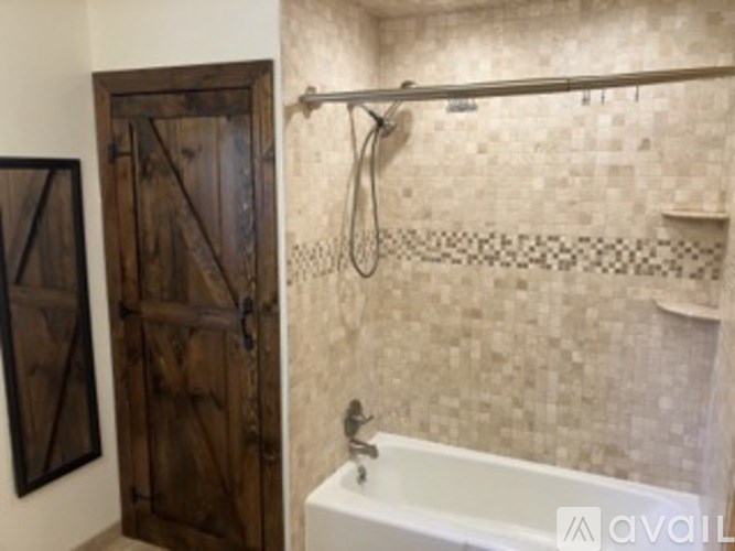 A bathroom with a white tub and a wooden door.