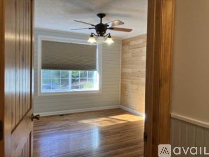 A room with a ceiling fan and wooden flooring.