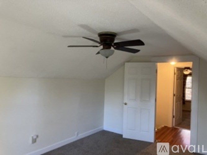 A room with a ceiling fan and a door.