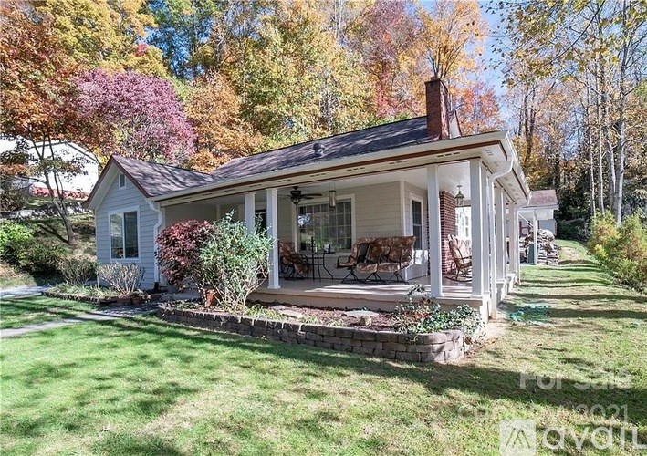 A house with a porch surrounded by a green lawn.