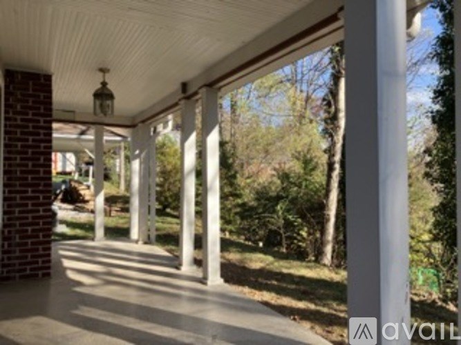 A porch with white columns and a brick pillar.