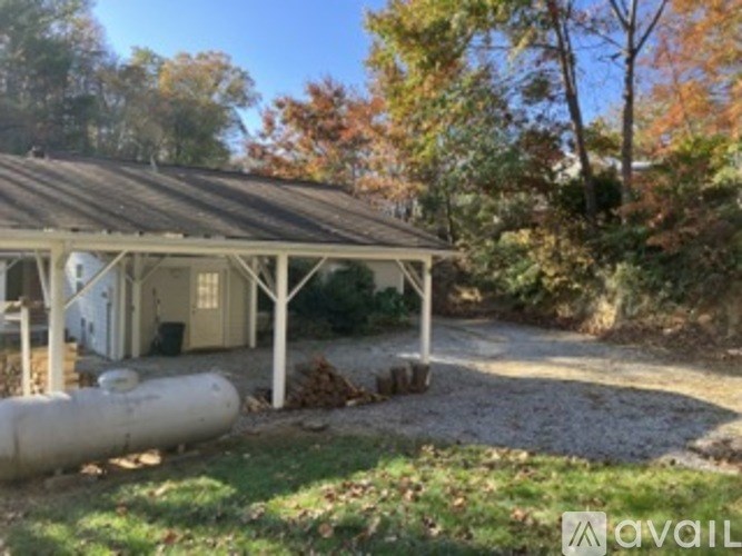 A small white building with a brown roof surrounded by trees.