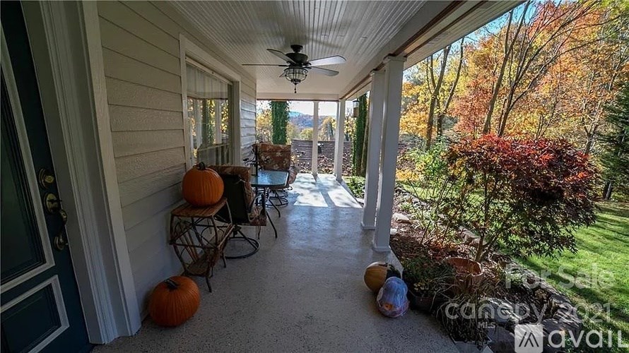 A porch with a ceiling fan and pumpkins on the floor.