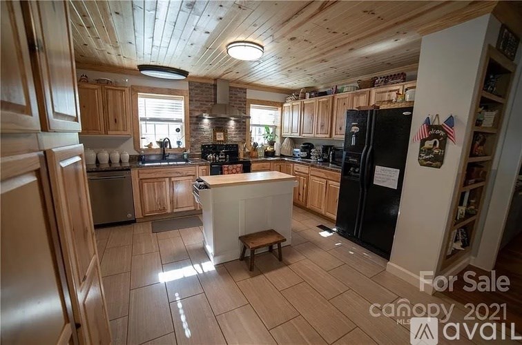 A kitchen with wooden cabinets and a black fridge is for sale.