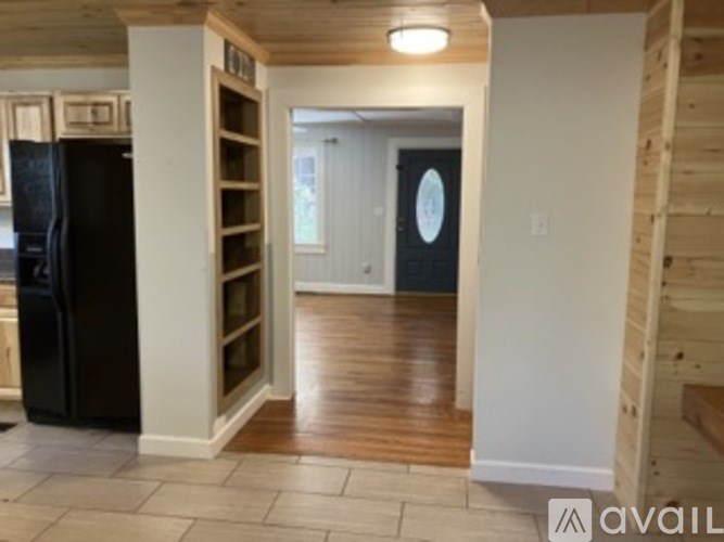 A kitchen with a black fridge and wooden floors.