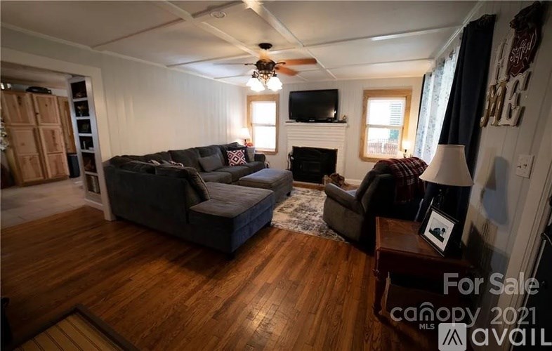 A living room with a couch, chair, and a television on the wall.