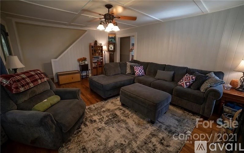 A living room with a grey couch and a rug on the floor.