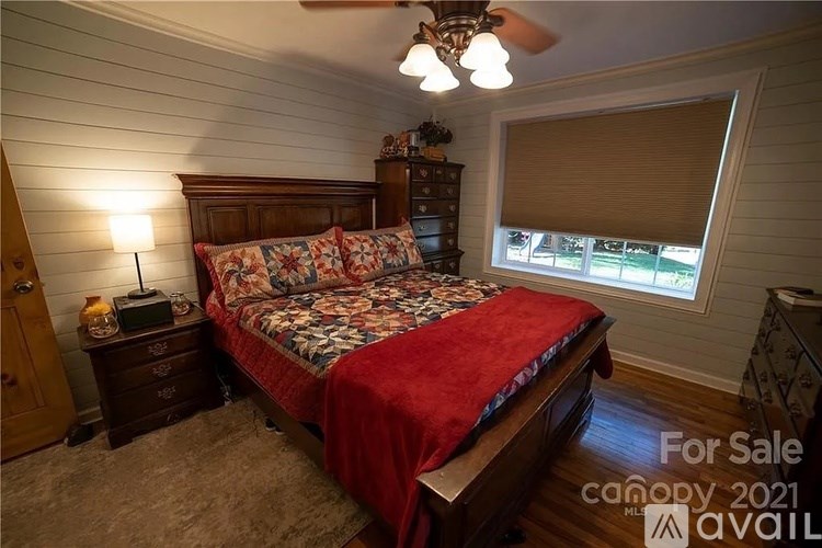 A bedroom with a bed, dresser, and window with blinds.