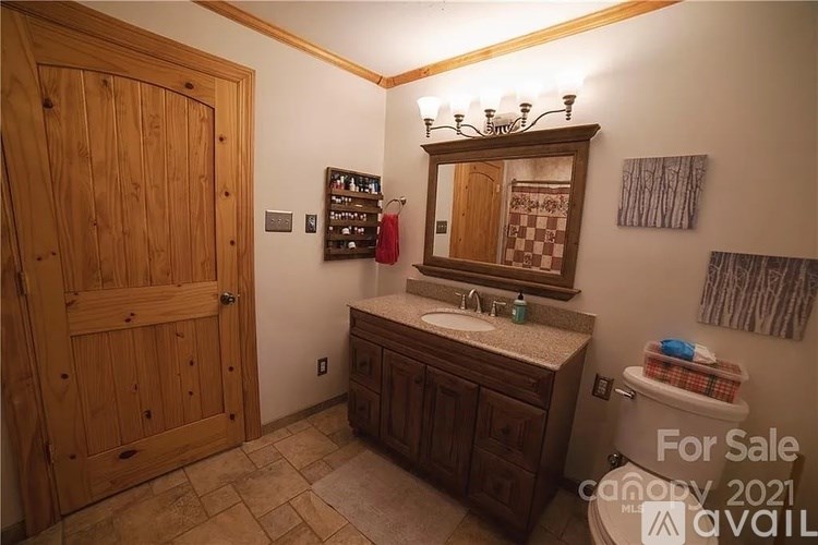 A bathroom with a wooden door and a sink with a mirror above it.