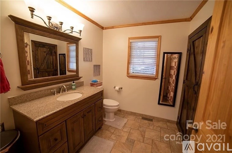 A bathroom with a sink, toilet, and a mirror.