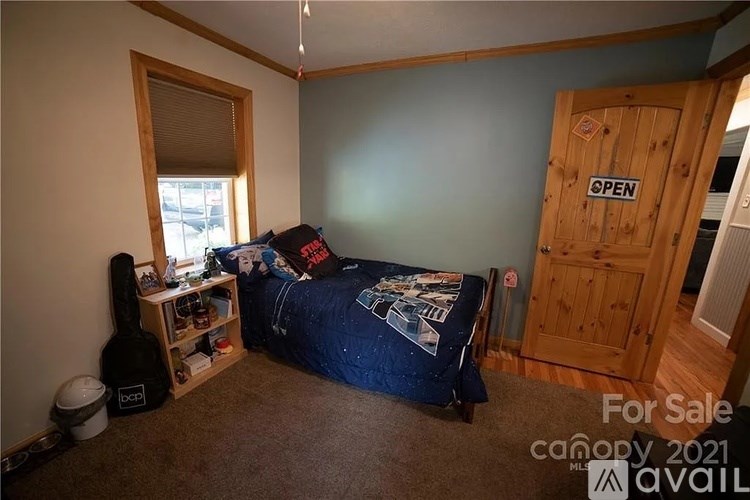 A room with a bed, a guitar case, and a window.