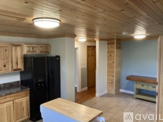 A kitchen with wooden cabinets and a black fridge.