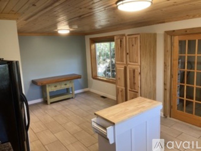 A kitchen with a black fridge, wooden cabinets, and a bench.