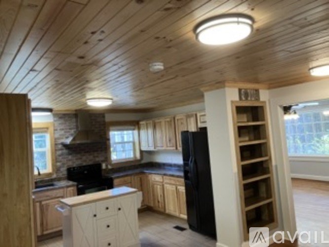A kitchen with wooden cabinets and a black refrigerator.