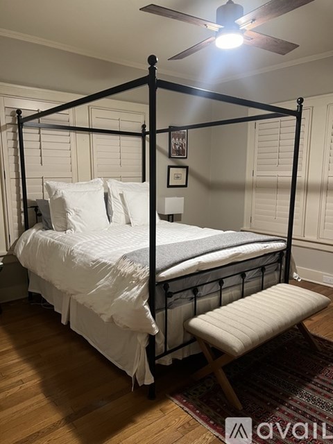 A bed with a white comforter and pillows is in a room with a ceiling fan.
