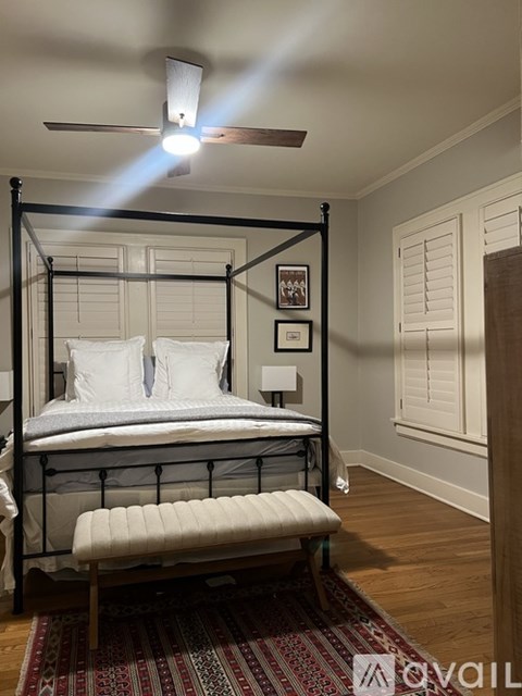 A bed with a white mattress and a white pillow is in a room with a ceiling fan.