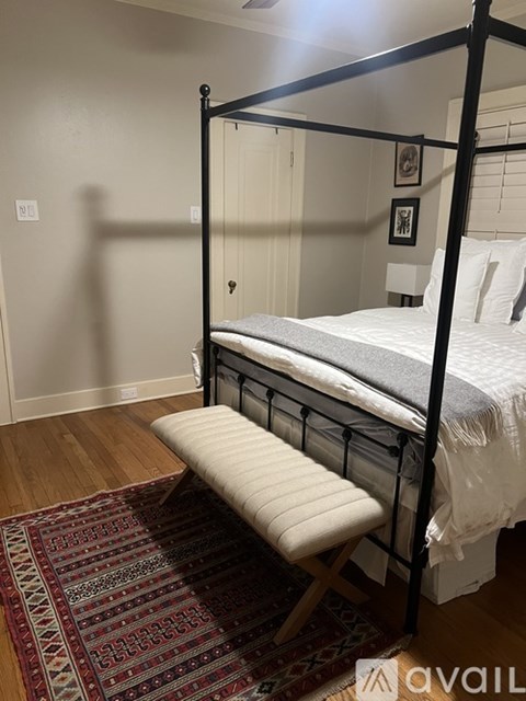 A bed with a white mattress and a white pillow is on a wooden floor.