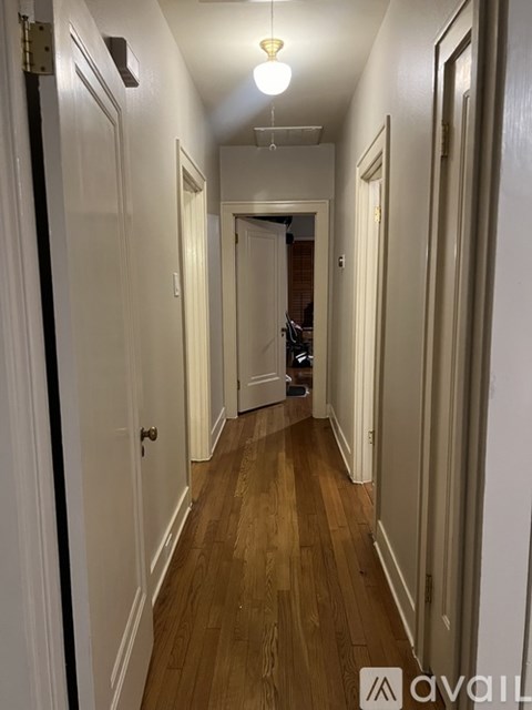 A long hallway with white walls and wood floors.