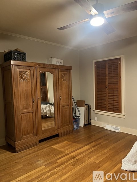 A room with wooden floors and a wooden cabinet with a mirror on top.