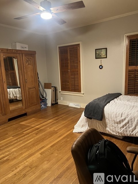A room with a bed, a chair, and a cabinet with a mirror.